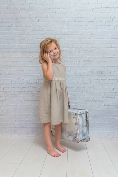Kız, bebek elbise beyaz tuğla duvar arka çanta, telefonla konuşmak