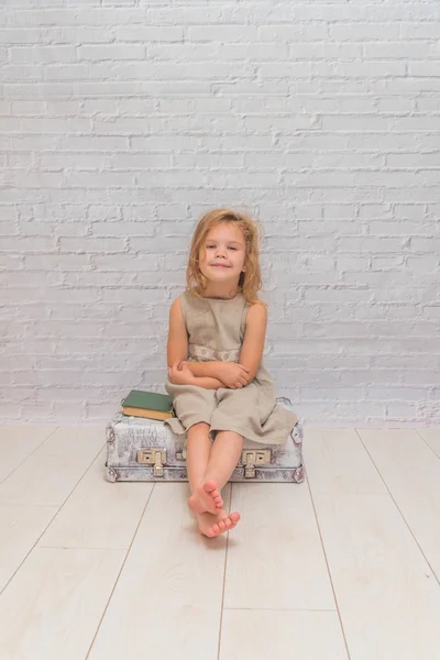 Kız Bebek Elbise Üzerinde Beyaz Tuğla Duvar Arka Plan Bavul — Stok fotoğraf