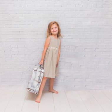 Kız, çocuk çanta beyaz tuğla duvar arka plan üzerinde