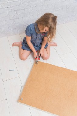 Kız, çocuk yeni bir tablo, bir beyaz tuğla duvar zemin üzerinde toplar.