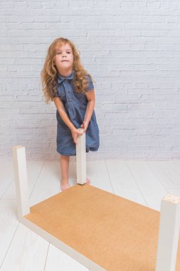 Kız, çocuk yeni bir tablo, bir beyaz tuğla duvar zemin üzerinde toplar.