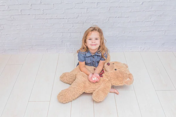 Девочка Ребенок Лечит Игрушечного Медведя Таблетка Перед Белой Кирпичной Стеной — стоковое фото