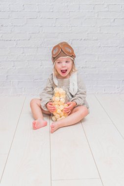 bir kız, bir pilotun kask içinde bir kavanoza çelenk ile katta oturan çocuk