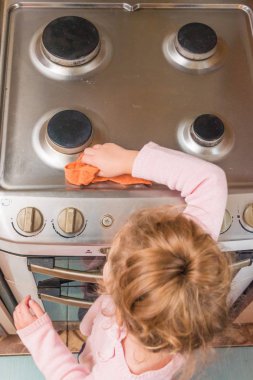 the Girl, child washes stove for cooking, in the kitchen