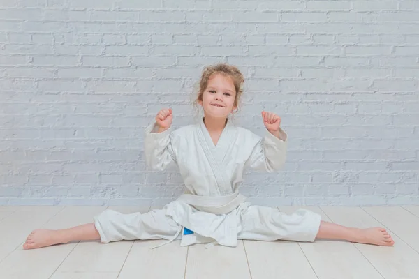 the girl, a child in a kimono on karate training works out blows and greeting