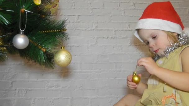 Ένα Κορίτσι Παιδί Διακοσμεί Χριστουγεννιάτικο Δέντρο Φόντο Λευκό Τούβλο Τοίχο — Αρχείο Βίντεο