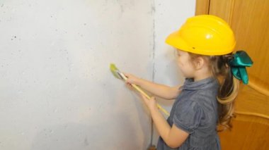 Kız, bir çocuk bir kask içinde fırça beyaz duvar boyama