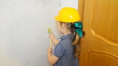 Kız, bir çocuk bir kask içinde fırça beyaz duvar boyama