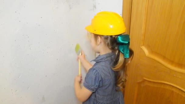 女の子 ヘルメット 子供は白い壁を塗るブラシします — ストック動画