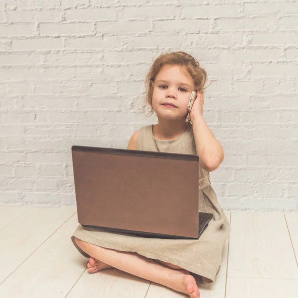 Kız, beyaz duvara karşı bir dizüstü çalışan çocuk işkadını