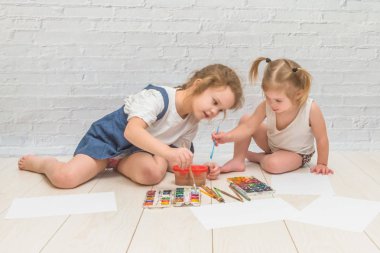 kız çocuk berabere bir fırça ve suluboya, boyalar, kağıt ve giyim bir sayfasına