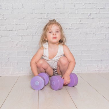 Kız, çocuğu meşgul Fitness dumbbells ile karşı bir 