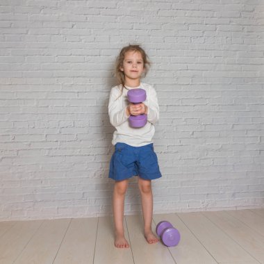 Kız, çocuğu meşgul Fitness dumbbells ile karşı bir 