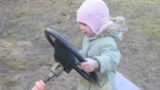 Дитина, дівчина грає, тримає кермо автомобіля і вона збирається — стокове відео