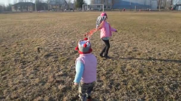 Un bambino, una ragazza che corre attraverso un prato, facendo volare un aquilone, una lite . — Video Stock