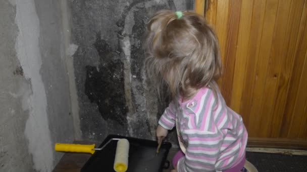 女の赤ちゃんのブラシは壁紙のための石壁の接着剤を塗りつぶす — ストック動画