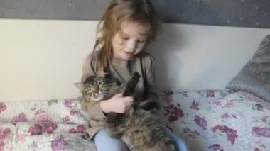 yatakta bir nazik kabarık kedi ile bir kız oturur