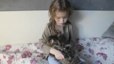 yatakta bir nazik kabarık kedi ile bir kız oturur