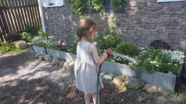 La muchacha veraniega con la regadera regando las flores — Vídeos de Stock