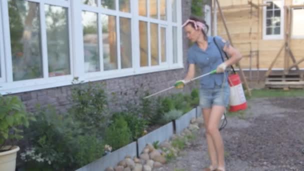 Gardener menina embaçada trata flores com fertilizante — Vídeo de Stock