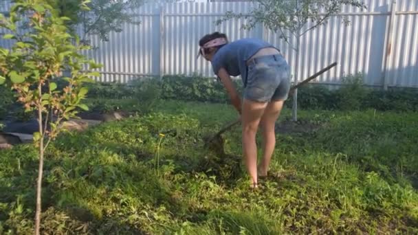 Meisje de tuinman verwijdert het gras hark — Stockvideo