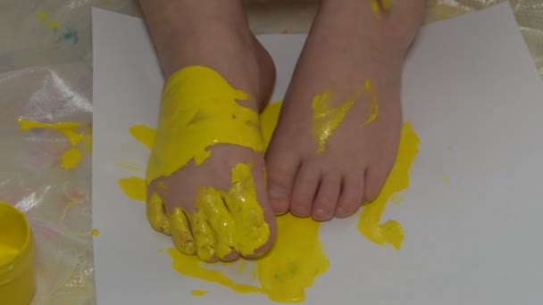아이는 바닥에 앉아 페인트와 브러시로 그립니다 — 비디오