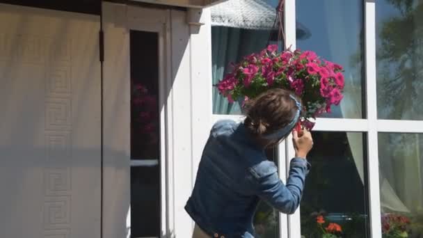 家の入り口で花を剪定する女の子の庭師 — ストック動画