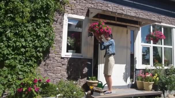 女孩园丁在房子的入口处修剪花 — 图库视频影像