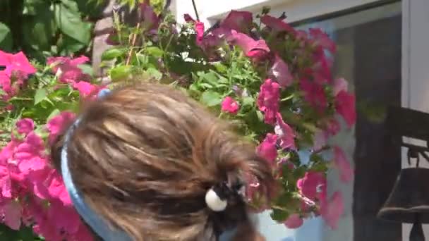 Flickan trädgårdsmästare beskärning blommor vid ingången till huset — Stockvideo