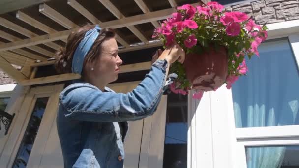 De meisje tuinman snoeien bloemen bij de ingang van het huis — Stockvideo