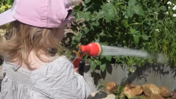 La bambina fiori giardino annaffiatoio dal tubo — Video Stock