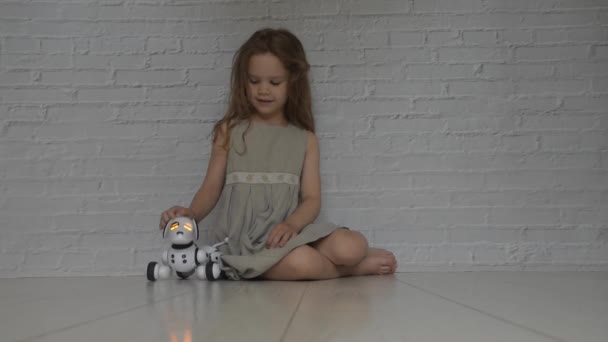 Играющая девочка заботится о собаке-роботе — стоковое видео