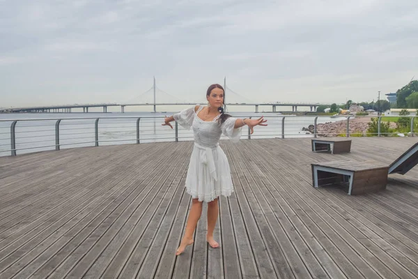 Dziewczyna na nabrzeżu w białej sukni taniec — Zdjęcie stockowe