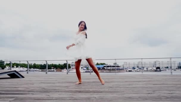 La chica frente al mar en un vestido blanco bailando — Vídeo de stock