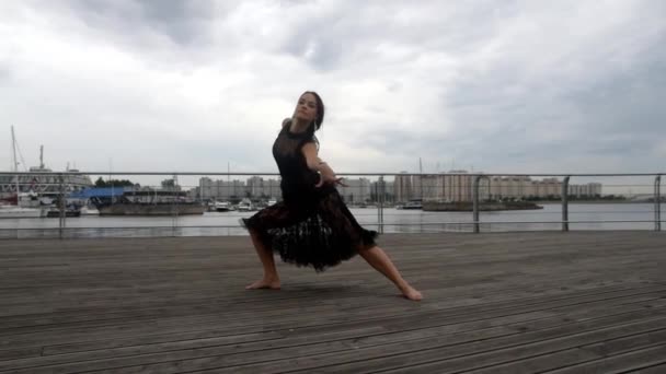 La fille au bord de l'eau dans une robe noire dansant — Video