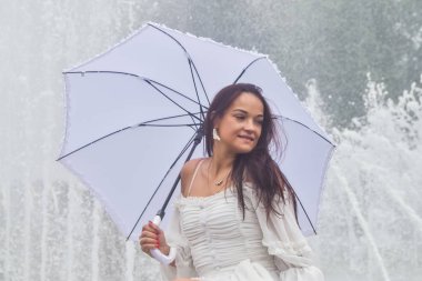 bir üzerinde çeşme tarafından beyaz elbise ve şemsiye güzel kız 