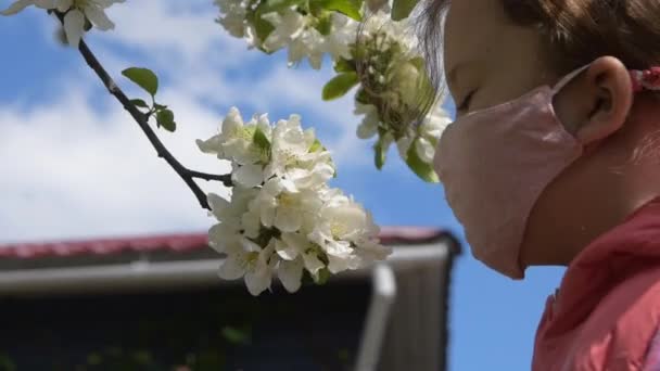 Un bambino in maschera annusa fiori Virus dell'allergia all'esterno — Video Stock