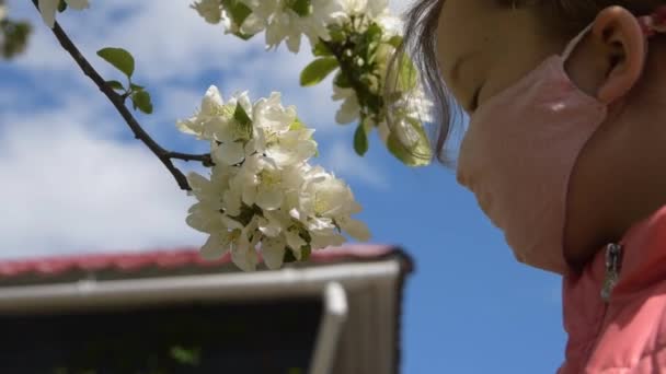 Uma criança na máscara fareja flores vírus da alergia fora — Vídeo de Stock