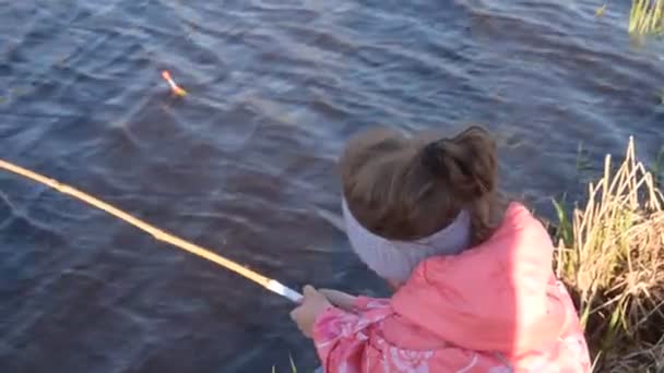 egy gyermek horgászbottal a vízen nézi a tutajt