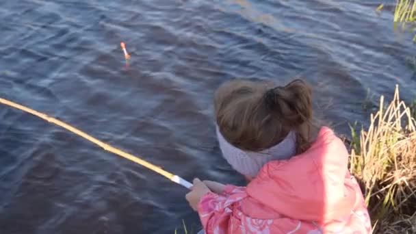 Ett barn med fiskespö vid vattnet tittar på flottören — Stockvideo