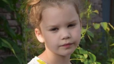 Bir kız çocuğu koklamak için bir çiçek çıkarır.