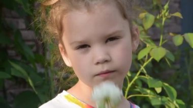 Bir kız çocuğu koklamak için bir çiçek çıkarır.