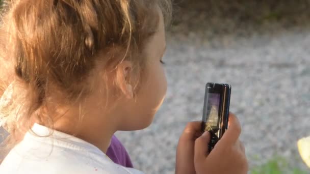 Dziecko emocjonalnie pisze przez telefon na zewnątrz. — Wideo stockowe