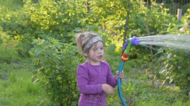 Ένα παιδί με λάστιχο και πότισμα μπορεί να ποτίσει τον κήπο — Αρχείο Βίντεο