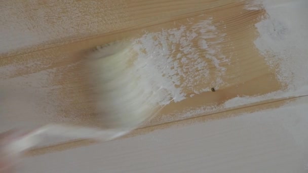 La mano del trabajador en el primer plano pinta la pared de madera con el pincel de rodillo con la pintura blanca — Vídeos de Stock