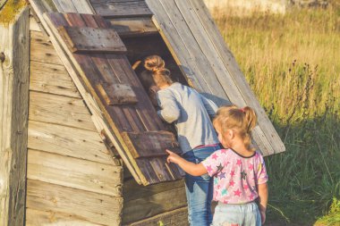 Güneşli yaz gününde kuyudaki bir çocuk kovayla su çeker ve metal bir bardaktan su içer.