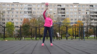 Genç ve güzel kız spor yapıyor dışarıda kettlebell fitness yapıyor.
