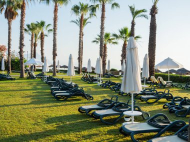 Otel, Türkiye'nin Güneydoğu bölümü için tipik sabahın erken saatlerinde. Sun'ın bahçesinde deniz kenarında şezlong vardır. Kemer, Türkiye.