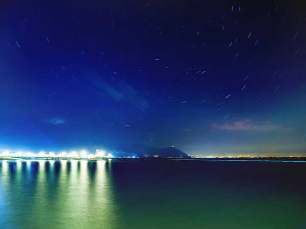 Star tracks over Mediterranean sea and Antalya town. Long exposure of starry night sky. Turkey.