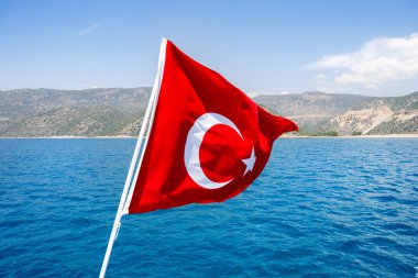 Güneşli bir günde Türkiye'nin Akdeniz'e karşı rüzgarda sallayarak bayrak.